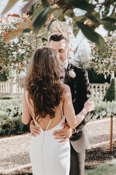 Bride and groom holding each other in gardens