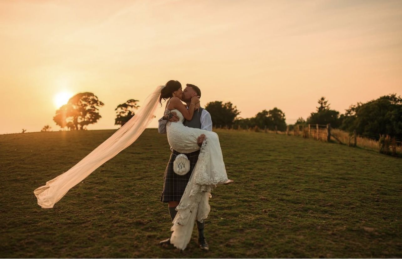 Groom carrying bride at sunset
