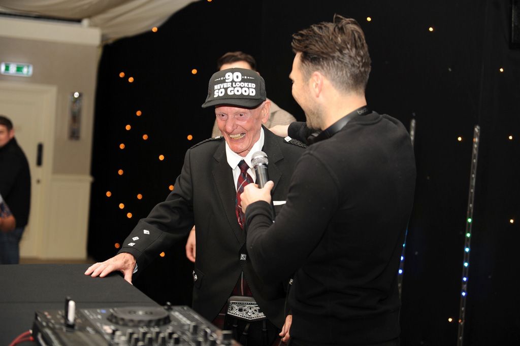 Man with 90th birthday hat on next to Mark Wright
