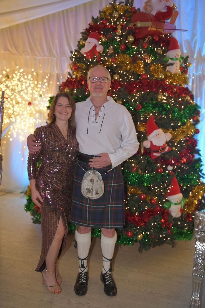 Kilted man and lady in front of Christmas tree