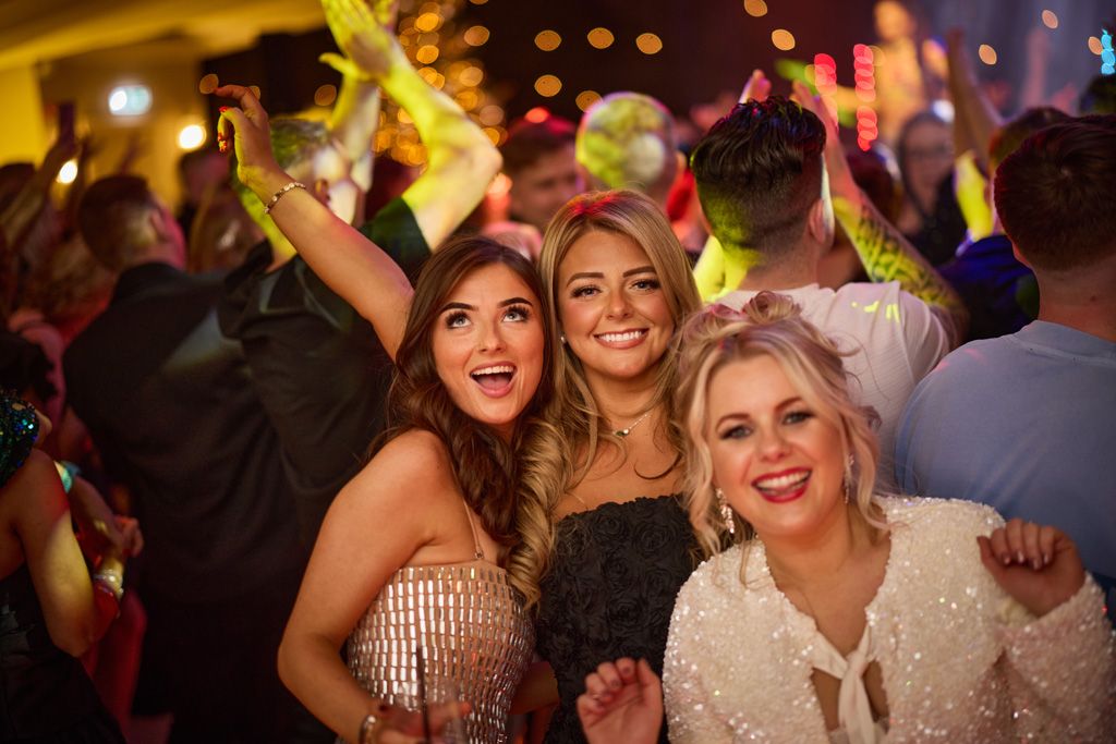 Three girl smiling on busy dancefloor