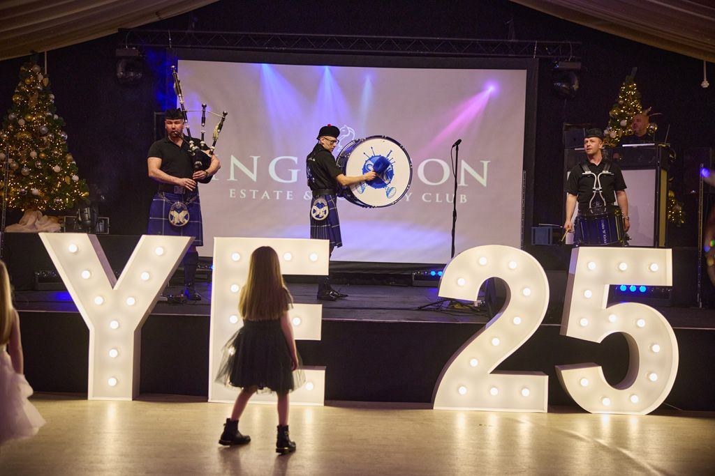 Pipe band on stage with little girl watching