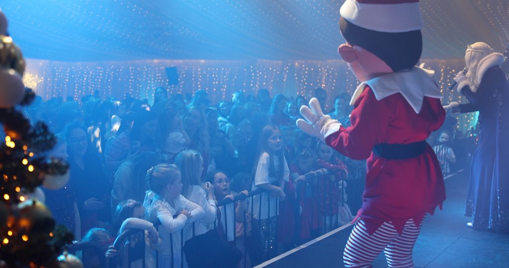 Elf in front of large crowd of children